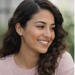 Eine Frau mit langen, gewellten braunen Haaren und einem hellrosa Oberteil lächelt und schaut nach links. Im Freien, mit unscharfem Grün im Hintergrund, wirkt sie zufrieden, nachdem sie einen Termin bei der Adressänderung GmbH Notar wahrgenommen hat.