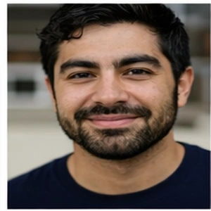 Ein Mann mit dunklen Haaren und Bart, der ein marineblaues Hemd trägt, lächelt vor einem unscharfen Hintergrund in die Kamera - ideal für die Darstellung eines Notars Erbrecht Berlin professional.