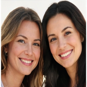 Zwei Frauen mit langen Haaren lächeln eng beieinander in die Kamera, beide in hellen Oberteilen, vor einem sanft verschwommenen Hintergrund - perfekte Partner, bereit, UG online gründen.