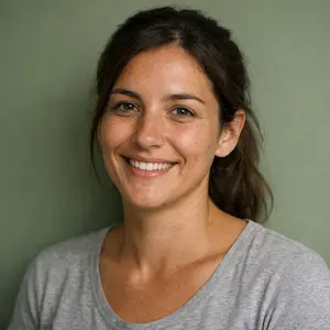 Eine Frau mit langen braunen Haaren in einem lockeren Pferdeschwanz lächelt in die Kamera. Sie trägt ein hellgraues T-Shirt und steht vor einem unifarbenen grünen Hintergrund. Sie verkörpert Zuversicht - perfekt für das Profil Ihres Teams Kettengründung.